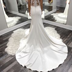 a woman in a wedding dress looking at herself in the mirror