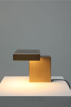 an illuminated table lamp sitting on top of a white counter next to a gray wall