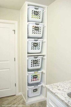 a white shelf filled with plastic baskets next to a marble counter top and sink in a bathroom