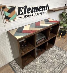 an entertainment center with wooden shelves and rugs on the floor in front of a sign that reads element wood design