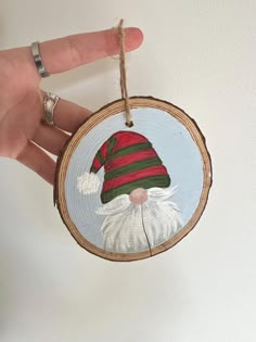 a hand holding a christmas ornament with a santa clause on it's face