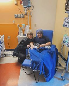 two people sitting in a hospital bed smiling for the camera