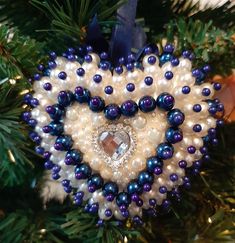 a heart shaped ornament hanging from a christmas tree with blue and white beads