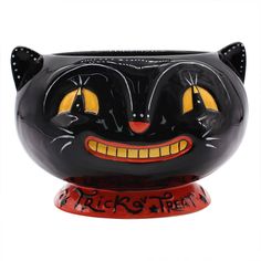 a ceramic black cat with yellow eyes and fangs on it's face is shown in front of a white background