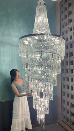 a woman standing in front of a chandelier with lots of lights on it