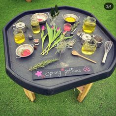 an outdoor picnic table is set up with various foods and drinks on it, along with a sign that says spring potions