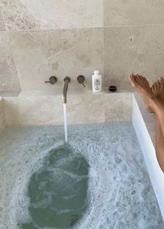 a person sitting in a bathtub with their feet up