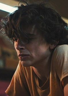 a young man with curly hair sitting down