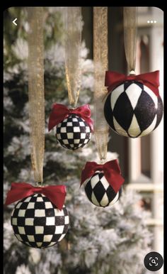 ornaments hanging from the ceiling in front of a christmas tree with red bows on them