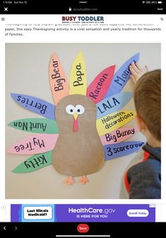 a little boy that is standing in front of a bulletin board with a turkey on it