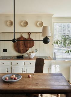 a wooden table sitting in the middle of a kitchen next to a potted plant