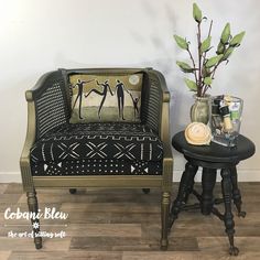 a black and gold chair next to a small table with a vase on top of it