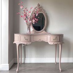 a pink vanity with mirror and flowers on it