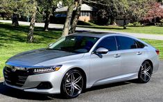 a silver car is parked on the side of the road in front of some trees