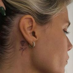 a woman's ear with a small rose tattoo on her left side behind the ear