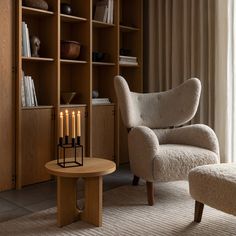 a living room filled with furniture and a book shelf next to a chair in front of a window