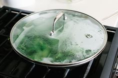 a pan filled with green liquid sitting on top of an oven burner next to a stove