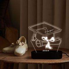 a light up graduation cap on top of a wooden table next to shoes and a pair of white tennis shoes