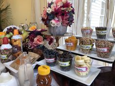 an assortment of fruit and nuts on trays in front of a vase with flowers