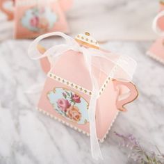 small pink boxes with bows on them are sitting on a table next to lavender flowers