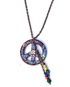 "A Boho peace sign necklace featuring a pendant in speckled turquoise blue and burgundy, with painted white flowers and tiny Swarovski crystal rhinestone accents! Dangling alongside the artful pendant, rows of genuine turquoise nuggets and colorful glass beads add flirty movement! And you have your choice of chain length so it will be the perfect length! Add this super-cute piece of Boho-style wearable art to your collection! Ceramic Pendant 1 1/4\" round, Antiqued Gold-plated Necklace w/ Lobste Bohemian Peace Sign Necklace For Gift, Boho Peace Sign, Peace Necklace, Peace Sign Necklace, Symbolic Jewelry, Ceramic Pendant, Genuine Turquoise, Gold Plated Necklace, Peace Sign