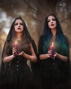 two women dressed in black holding candles