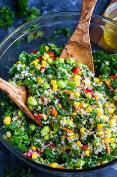 a bowl filled with rice and vegetables next to a wooden spoon on top of a table