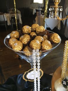 a glass bowl filled with lots of chocolates on top of a wooden table next to a chandelier