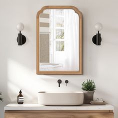 a white sink sitting under a mirror next to a wooden cabinet and potted plant