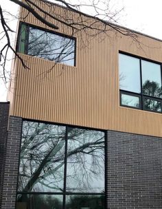 a large brown brick building with windows and trees in the backround, on a cloudy day