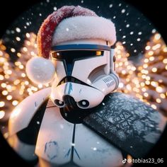 a star wars character wearing a santa hat and holding a snowboard in front of christmas lights