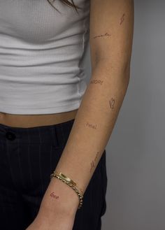 a woman's arm with writing on it and a gold chain around the wrist