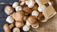 a bunch of mushrooms sitting on top of a wooden table next to a bag with a brown handle