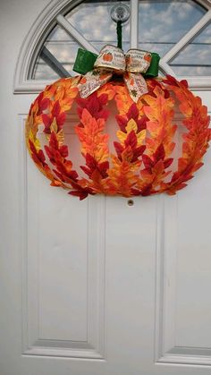 an orange wreath hanging on the front door with a green bow and ribbon around it