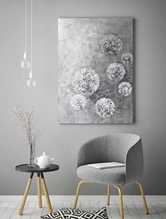 two chairs and a table in front of a gray wall with white flowers on it