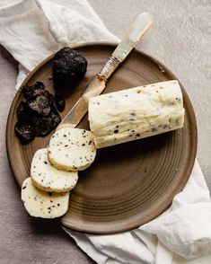 a brown plate topped with sliced up bananas and black raisins next to a knife