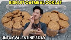 a man sitting in front of three plastic containers filled with oatmeal cookies