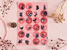 a pink calendar with animals and numbers on it next to dried flowers, berries and pine cones