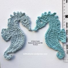 two crocheted seahorses are next to a ruler