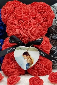 a teddy bear made out of red, white and blue roses with a heart on it