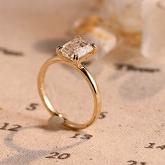 a close up of a gold ring with a diamond on it and flowers in the background