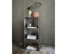 a metal shelf with some books and a potted plant on top, against a gray wall