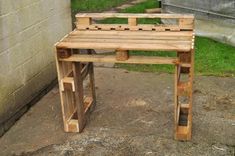 a wooden bench sitting on top of a sidewalk next to a brick wall and grass