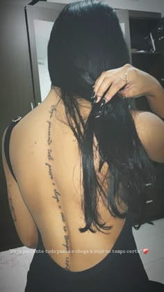 the back of a woman's body with writing on it, and her hand in her hair