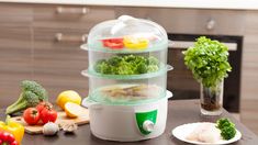 three containers with food in them sitting on a kitchen counter next to vegetables and broccoli