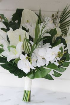 a bouquet of white flowers and greenery on a table