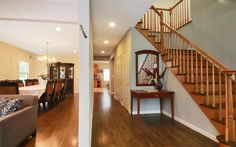 a living room and dining room area with hardwood flooring, stairs leading up to the second floor