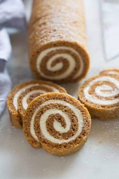 three cinnamon rolls on a counter with one cut in half and the other rolled up