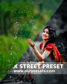 a woman in red sari is smiling while standing under the rain with her hands out