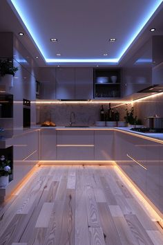 an empty kitchen with wooden floors and white cabinets, lights on the ceiling and floor